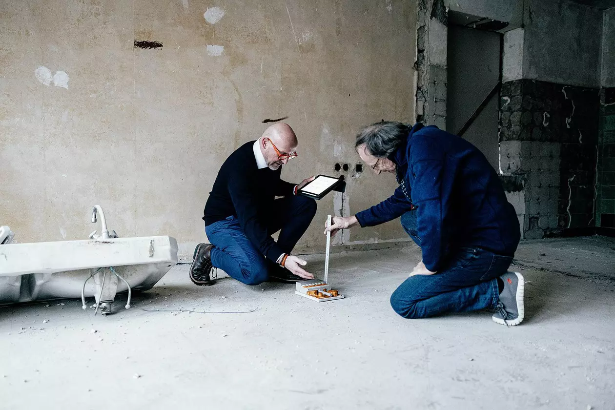 Deux planificateurs de construction mesurent la hauteur de structure approximative d'un chauffage au sol BEKOTEC-THERM sur le chantier d'un b&acirc;timent en r&eacute;novation
