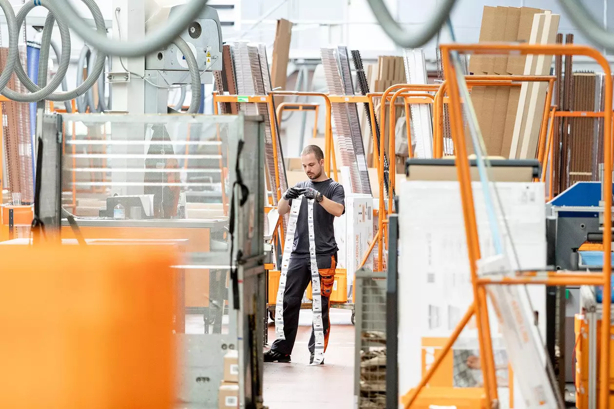 Un employ&eacute; masculin avec des &eacute;tiquettes autocollantes pour colis au milieu de l'entrep&ocirc;t.