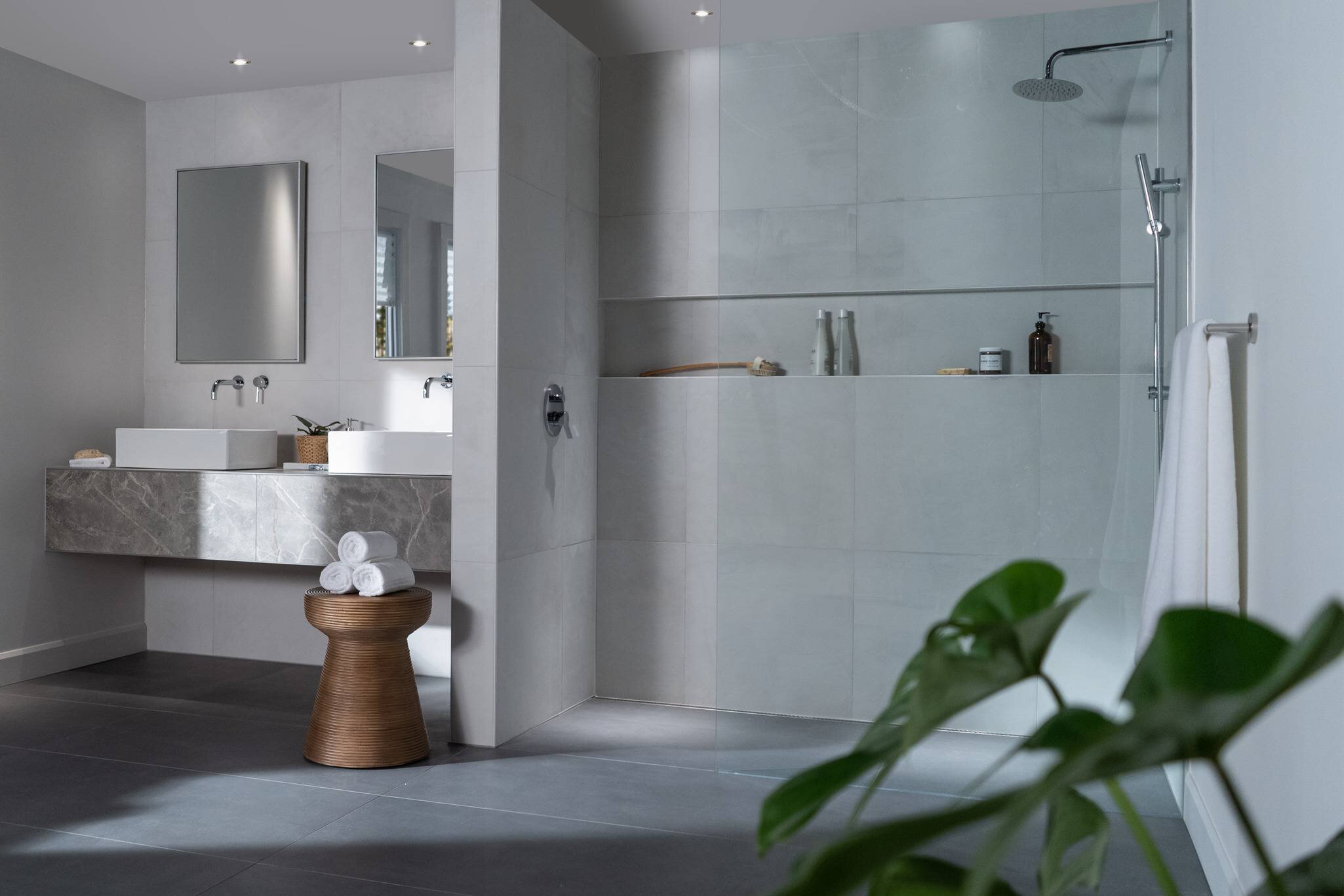 Grande salle de bain de tuile grise, douche incluant une longue niche horizontale, vanité avec double lavabo