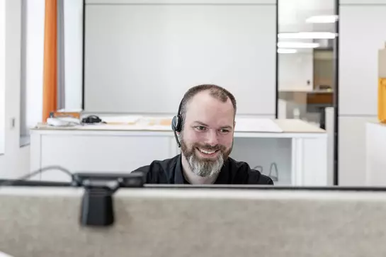 Un empleado de Schl&uuml;ter-Systems mira la pantalla del ordenador sonriendo.