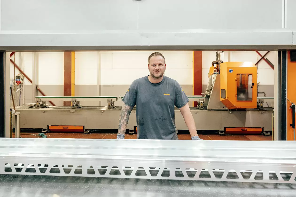 Mitarbeiter steht an einer Produktionsanlage, an dem ein Schl&uuml;ter-Balkonprofil entsteht