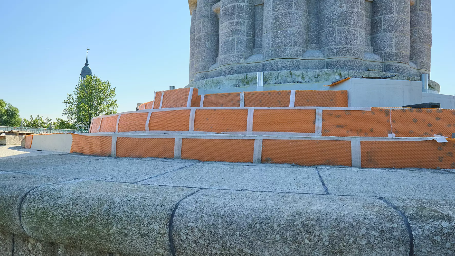 Sockeln p&aring; Bismarck-monumentet i skuggan. Naturstensbekl&auml;dnaden saknas p&aring; trappstegen och man ser den installerade ytdr&auml;neringen Schl&uuml;ter-TROBA-PLUS 8G.