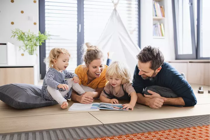 Family of four lying on the floor and looking at a Schl&uuml;ter brochure.