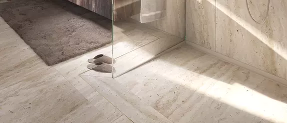 Sol carrel&eacute; beige d’une douche &agrave; l’italienne avec paroi en verre et caniveau de douche KERDI-LINE-VARIO