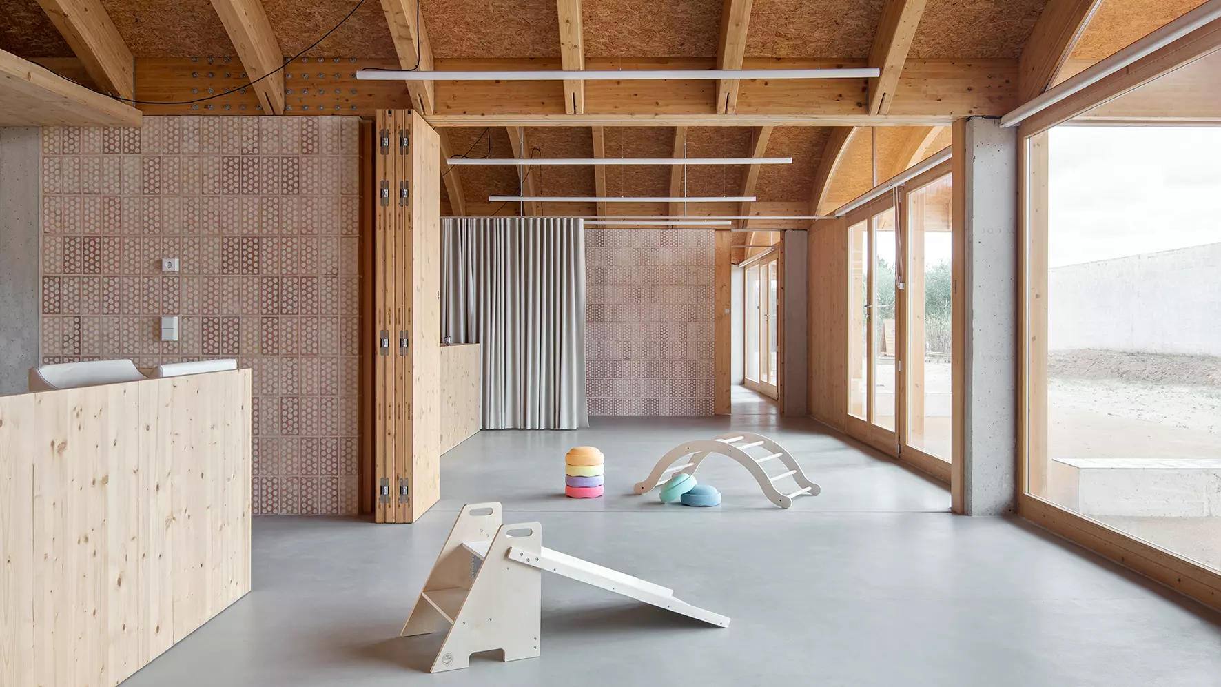 Amplio interior de la escoleta infantil en Muro, Mallorca, con juegos infantiles de madera