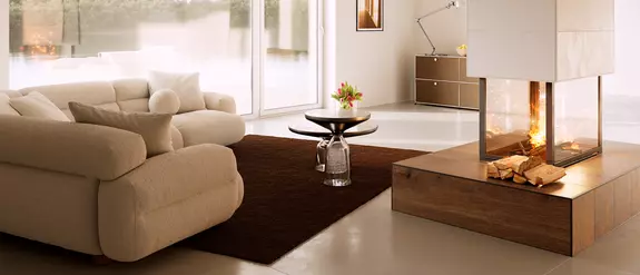 Blick in gro&szlig;z&uuml;gigen modernen Wohnbereich mit einem freistehenden, gefliesten Kamin, dessen Fliesenkanten mit dem Kantenschutzprofil Schl&uuml;ter-QUADEC abgeschlossen sind