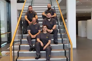 Mitarbeiter in Arbeitsklamotten sitzen auf einer Treppe