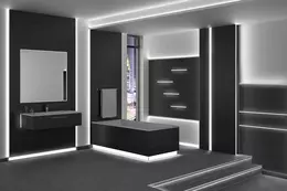 Zwart betegelde badkamer met lichtaccenten aan de wanden, het plafond, de rand van het bad en de plinten