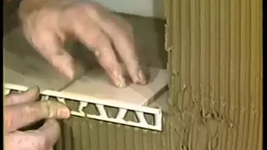 Sn&iacute;mek ze star&eacute;ho instrukt&aacute;žn&iacute;ho videa pro pokl&aacute;dku z 80. let ukazuje, jak se profil Schl&uuml;ter-SCHIENE pokl&aacute;d&aacute; na vnějš&iacute; hraně obkladu.