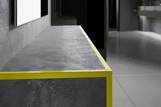 Schodišťov&yacute; stupeň s šed&yacute;m obkladem a žlutou kontrastn&iacute; hranou profilu.