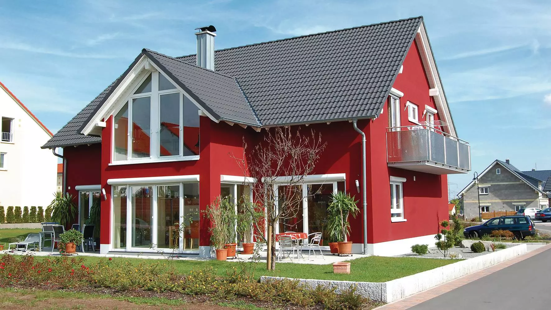 Een passiefhuis - met rode gevel en ramen met witte kozijnen - is ideaal voor DITRA-HEAT-E als aanvullende verwarming.