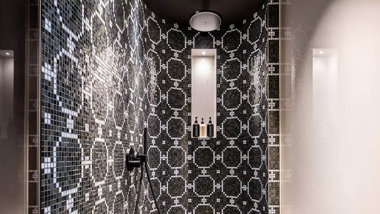 Douche &agrave; effet pluie avec paroi arri&egrave;re arrondie, niche &eacute;clair&eacute;e et carreaux d&eacute;coratifs noir et blanc
