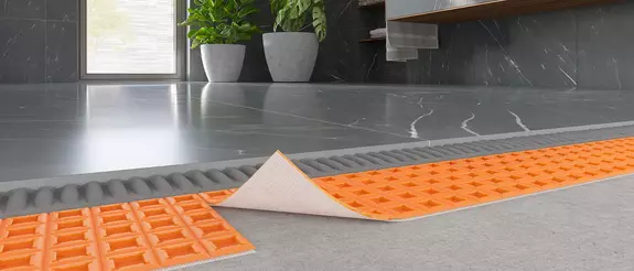 Selbstklebende Entkopplungsmatte Schl&uuml;ter-DITRA-PS verlegt in einem modernen Bad mit dunkelgrauen gro&szlig;formatigen Fliesen