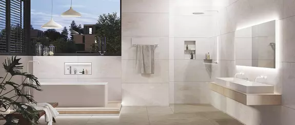 Salle de bains lumineuse avec baignoire sur pieds, douche accessible et nombreux produits Schl&uuml;ter.