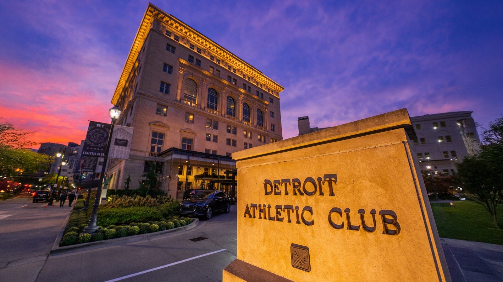 Detroit Athletic Club entrance sign and clubhouse facade illuminated at dusk