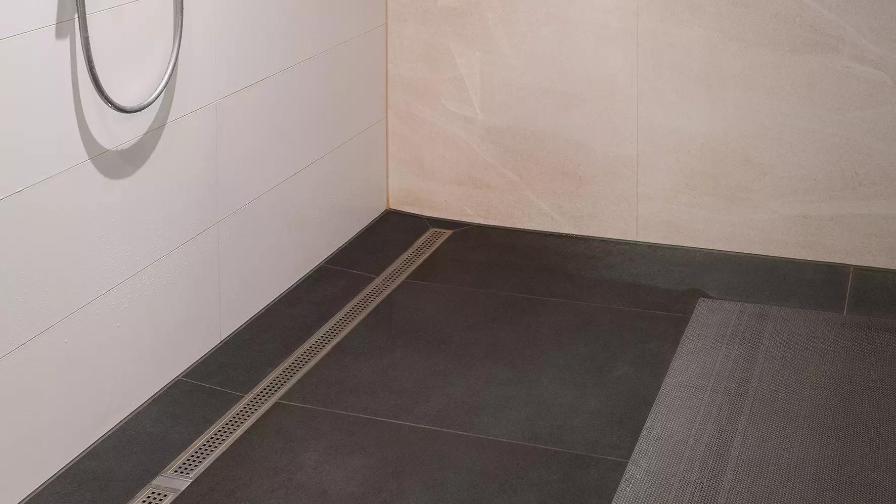 Die fertig gefliesten Duschen im Vereinsheim mit KERDI-LINE Duschrinne, dunkelgrauen Boden- und wei&szlig;en Wandfliesen