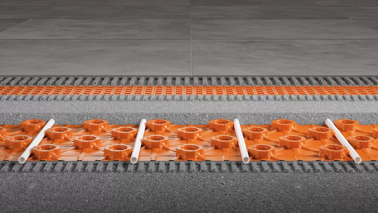 Repr&eacute;sentation en coupe d'une structure au sol avec la dalle &agrave; plots Schl&uuml;ter-BEKOTEC-EN-FK et la natte de d&eacute;solidarisation Schl&uuml;ter-DITRA, recouverte de grands carreaux de c&eacute;ramique gris pierre.