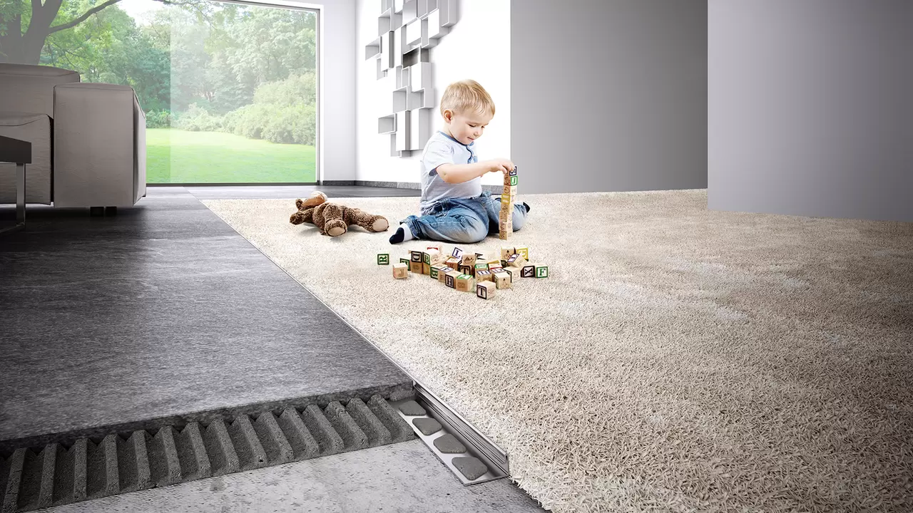 Kind speelt op een tapijt met blokken, op de voorgrond een doorsnede van de vloeropbouw met Schl&uuml;ter-profielen