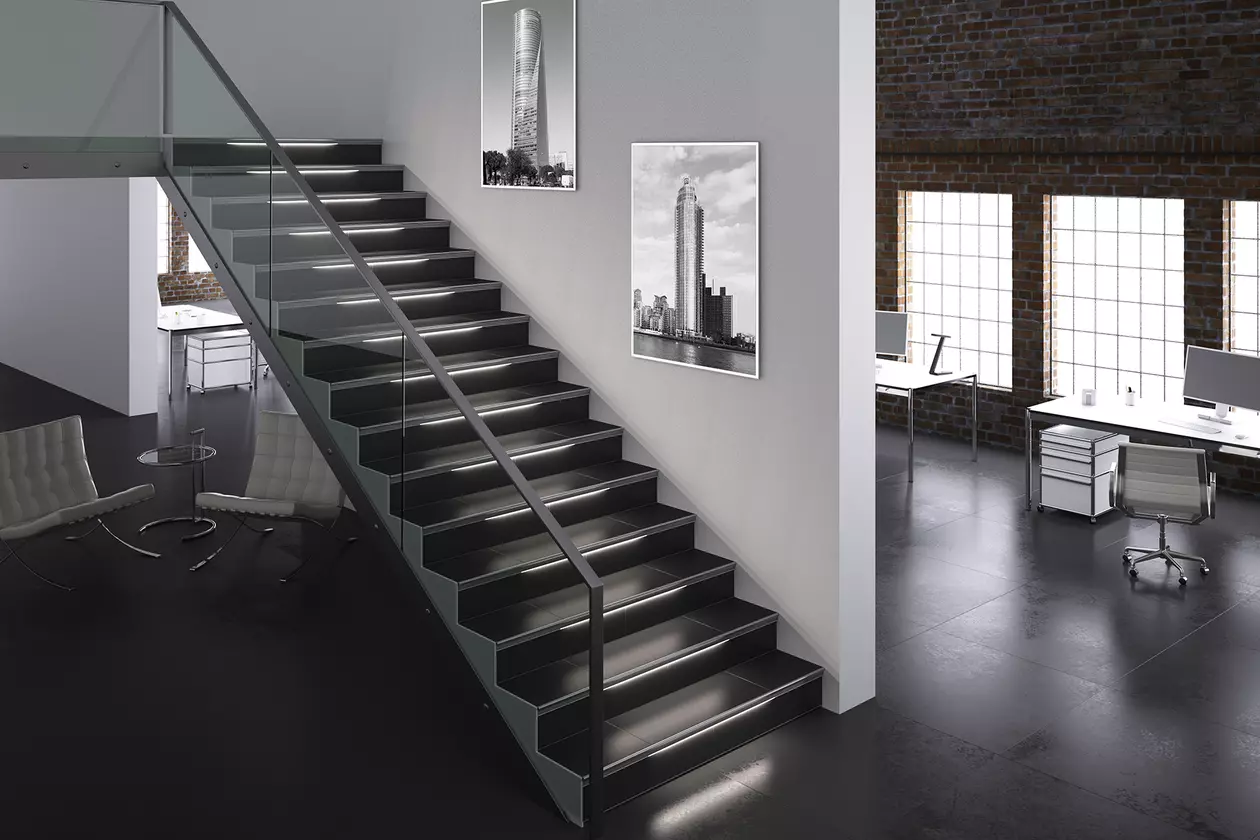 Mit einer Glaswand versehene, dunkel geflieste Treppe in einem Loft, die Treppenkanten sind beleuchtet
