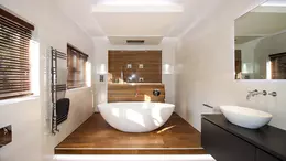 Blick in modernes Bad in Wei&szlig; und Holz mit freistehender Badewanne