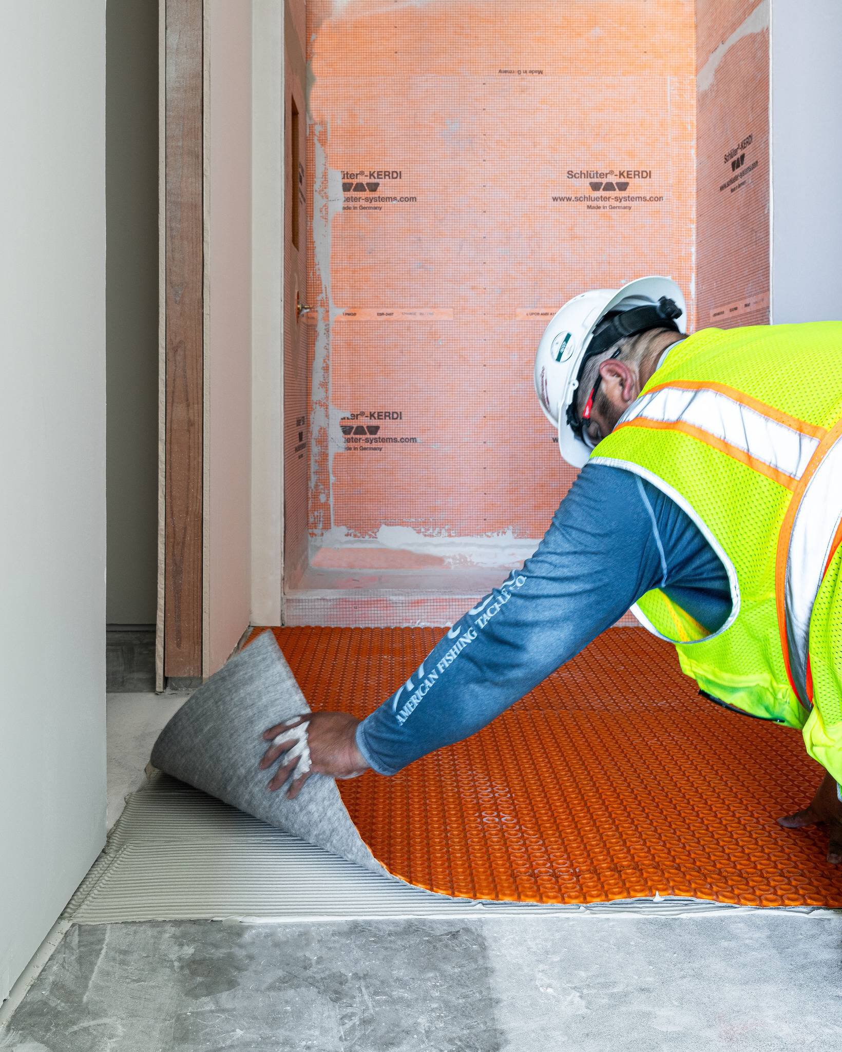 Un carreleur installant la membrane DITRA-HEAT de Schluter Systems pour le chauffage au sol.
