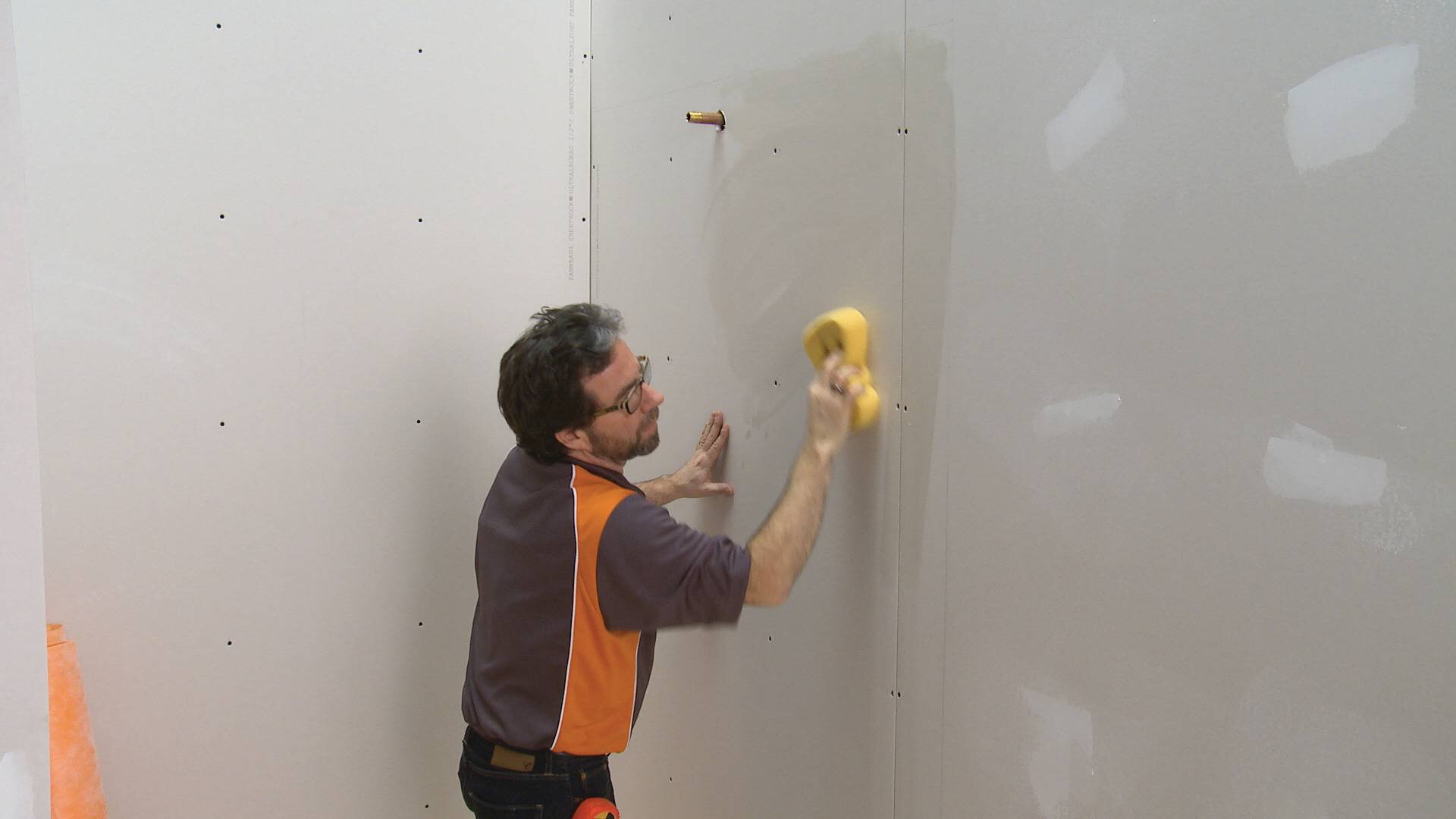Un homme lave le mur de gypse avant installation