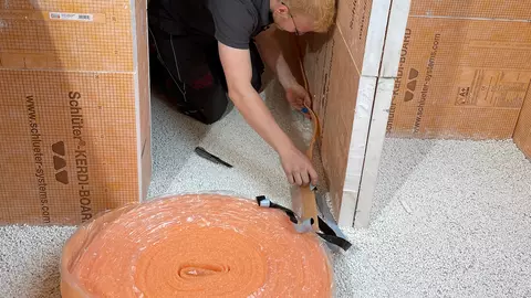 Een vakman plaatst de randstroken BEKOTEC-BRS, die dienen als overgang tussen vloer en wanden.
