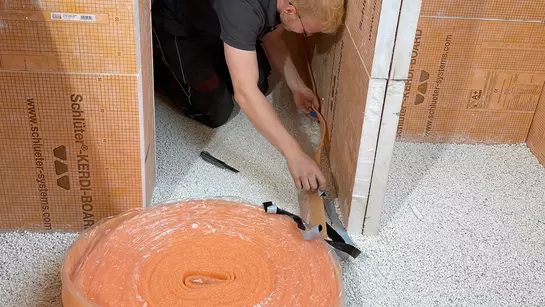 Řemesln&iacute;k pokl&aacute;d&aacute; obvodov&eacute; p&aacute;sky BEKOTEC-BRS, kter&eacute; slouž&iacute; jako přechod mezi podlahou a stěnami.
