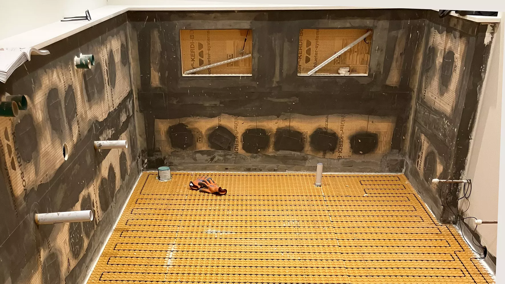 View of a bathroom under construction with niches in the wall and DITRA-HEAT electric heating mat and cables on the ground