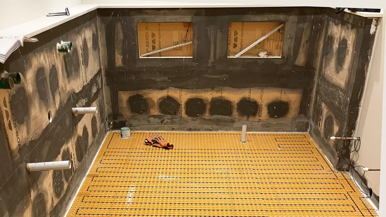 View of a bathroom under construction with niches in the wall and DITRA-HEAT electric heating mat and cables on the ground