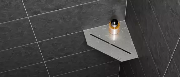 Close-up van een doucheplanchet Schl&uuml;ter-SHELF-E-S2 in het PURE-design aan donkergrijs betegelde wanden