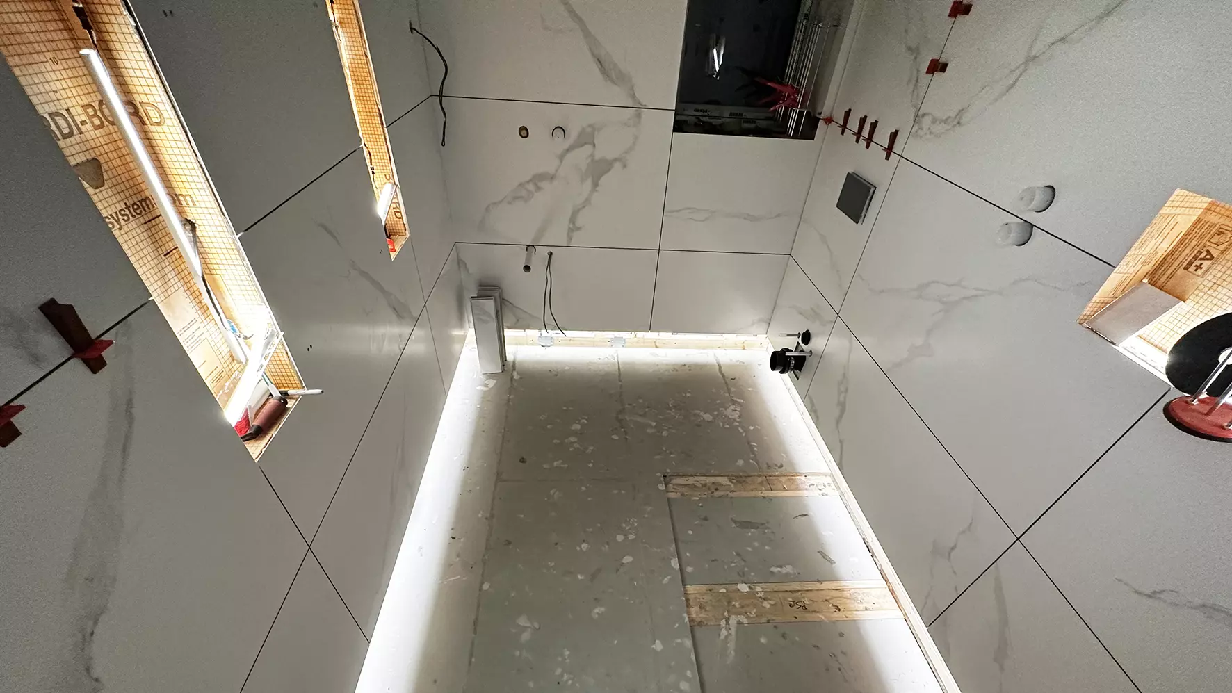 Shower area with large format marble tiles and LED-lit wall niches