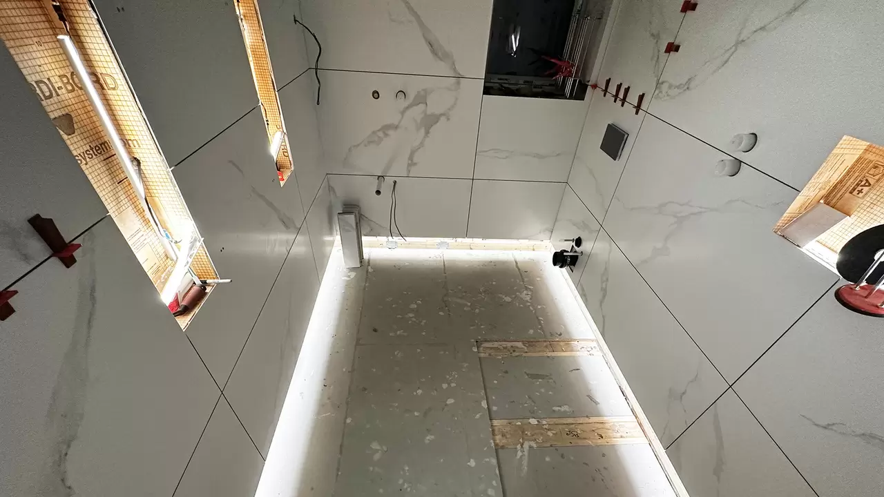 Shower area with large format marble tiles and LED-lit wall niches