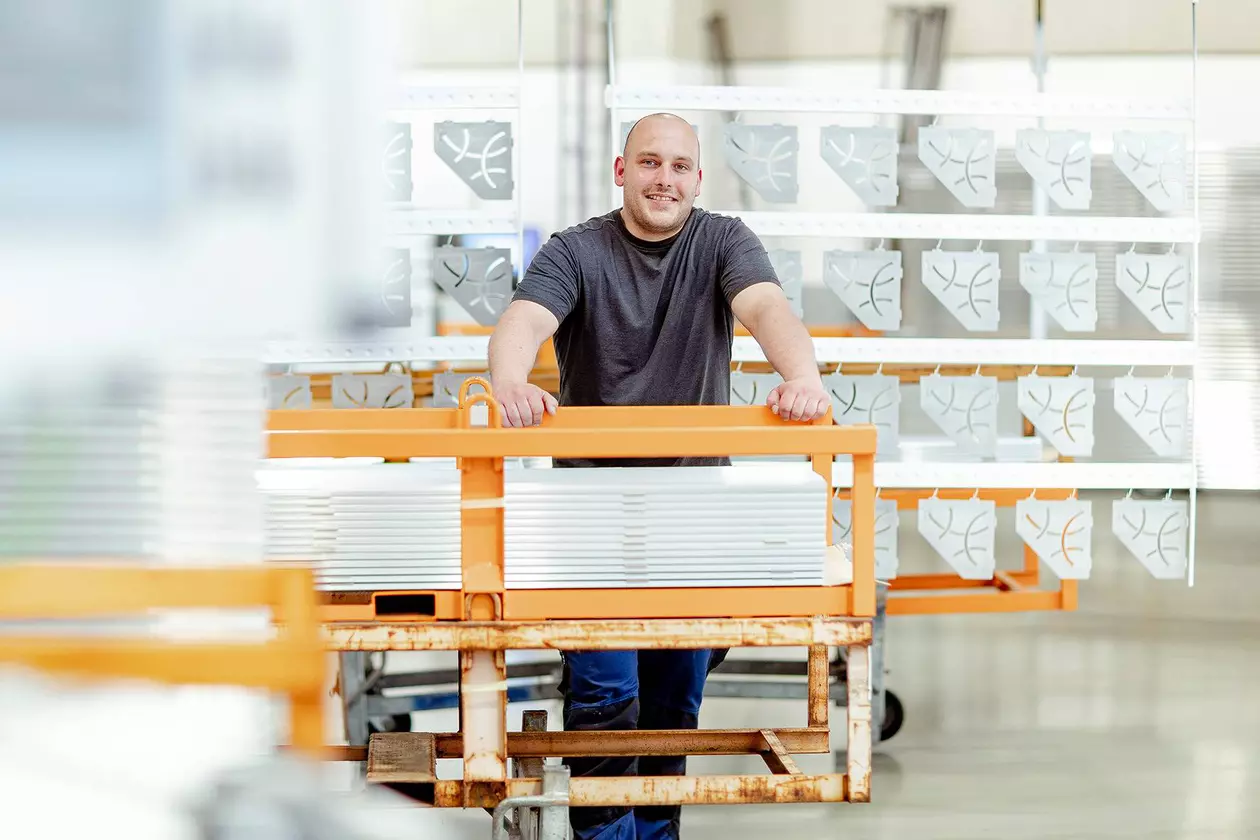 Zaměstnanec společnosti Schl&uuml;ter-Systems stoj&iacute; před lakovan&yacute;mi profily.