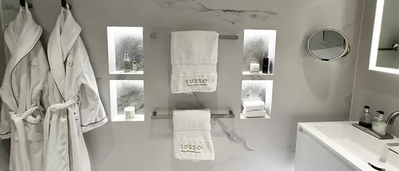 Bathroom wall with four LED-lit wall niches, robes and towels