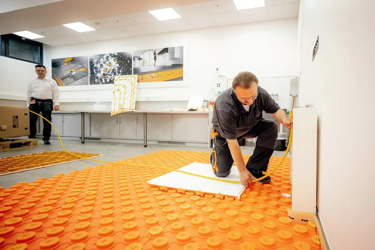 Vorf&uuml;hrmeister veranschaulicht die Verarbeitung der wassergef&uuml;hrten Fu&szlig;bodenheizung Schl&uuml;ter-BEKOTEK-THERM w&auml;hrend eines Seminars