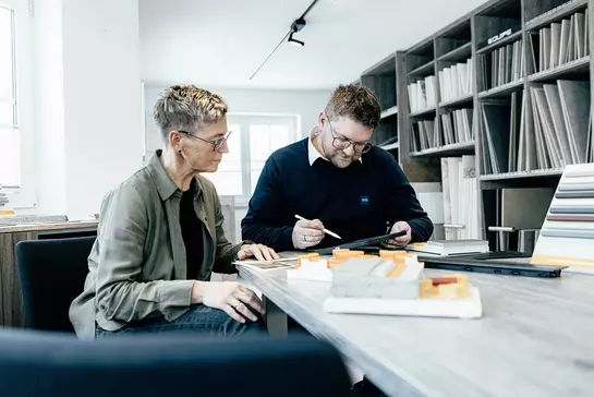 Een verkoopadviseur van Schl&uuml;ter-Systems legt aan een klant de kosten van de vloerverwarming BEKOTEC-THERM uit