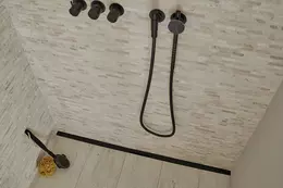Douche &agrave; l'italienne avec carrelage de couleur sable, robinetterie noire et caniveau filant Schl&uuml;ter-KERDI-LINE-VARIO en noir mat.