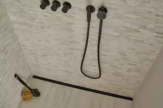 Douche &agrave; l'italienne avec carrelage de couleur sable, robinetterie noire et caniveau filant Schl&uuml;ter-KERDI-LINE-VARIO en noir mat.