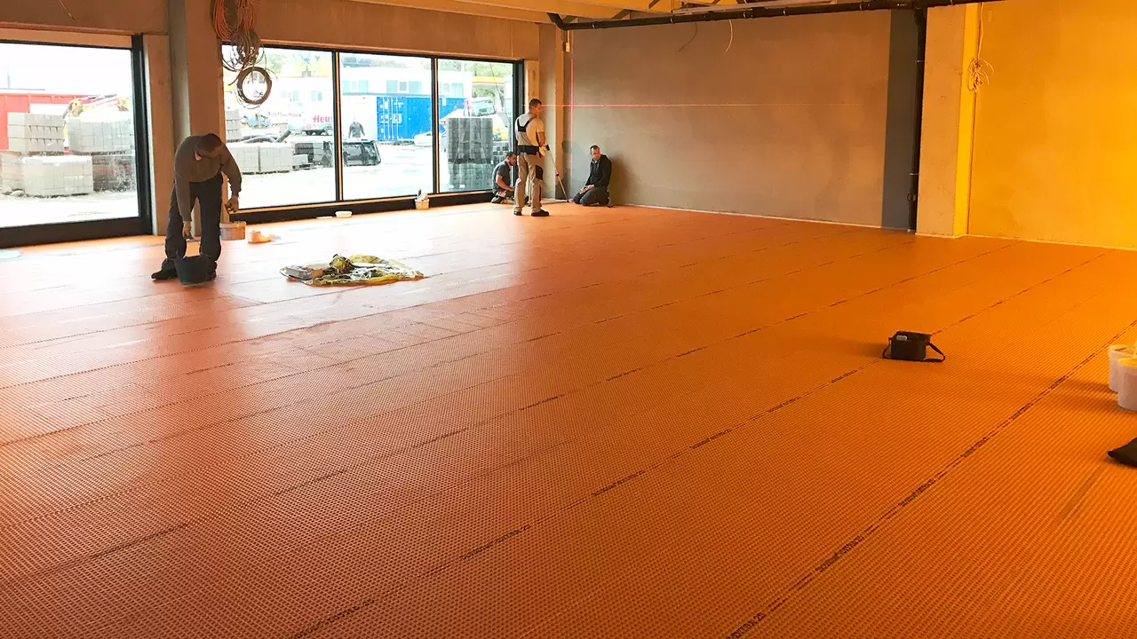 Instaladores empezando a colocar baldosas sobre Schl&uuml;ter-DITRA