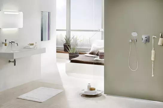 Salle de bain attenante avec douche ouverte, baie vitr&eacute;e et lit &agrave; l’arri&egrave;re-plan