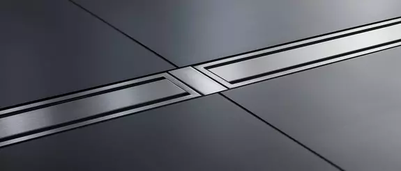 Schl&uuml;ter-KERDI-LINE in stainless steel on a dark tiled floor in the bathroom.
