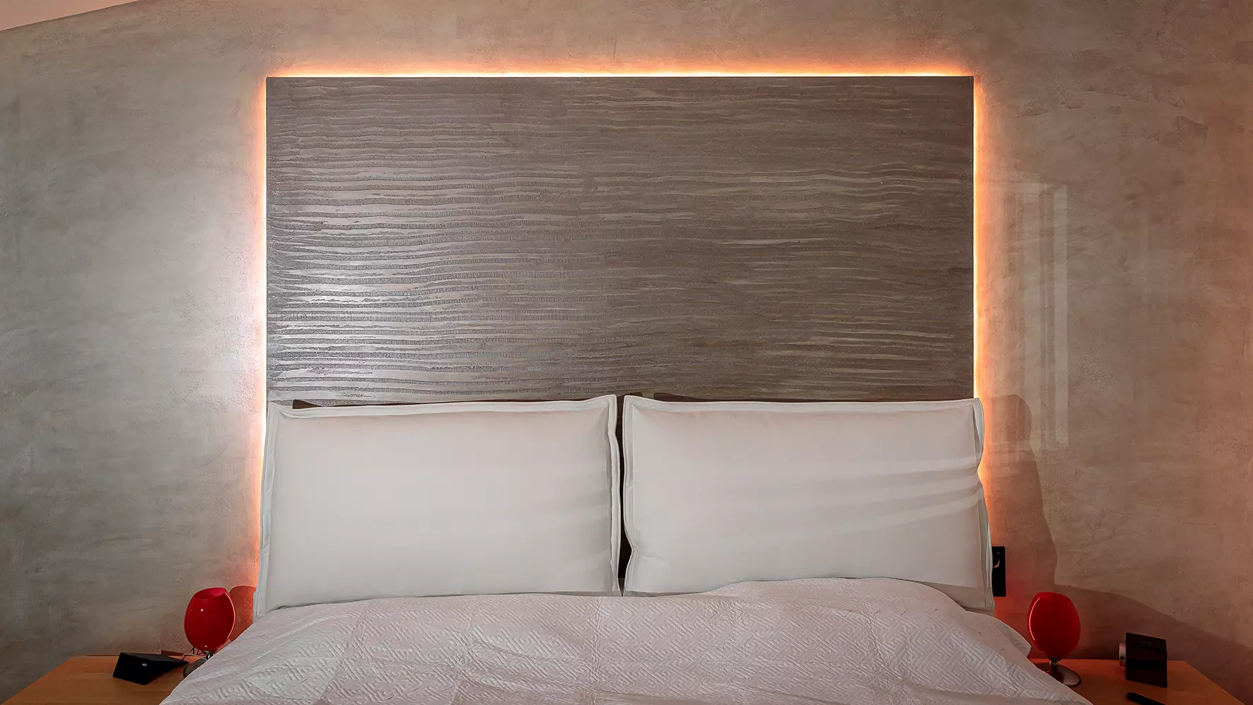 Vue d'une chambre &agrave; coucher avec un lit et t&ecirc;te de lit &eacute;clair&eacute;e