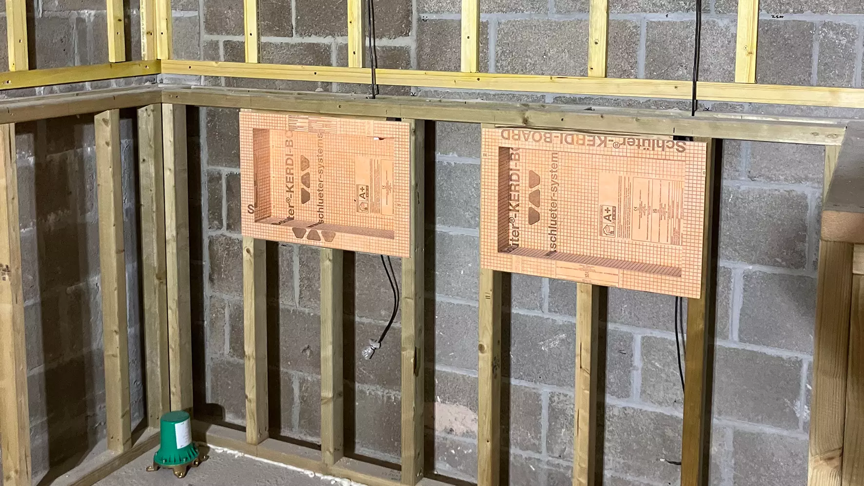 Bathroom wall under construction with two prefabricated Schl&uuml;ter niches installed on timberwood