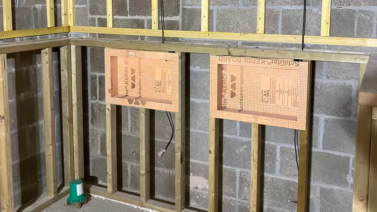 Bathroom wall under construction with two prefabricated Schl&uuml;ter niches installed on timberwood