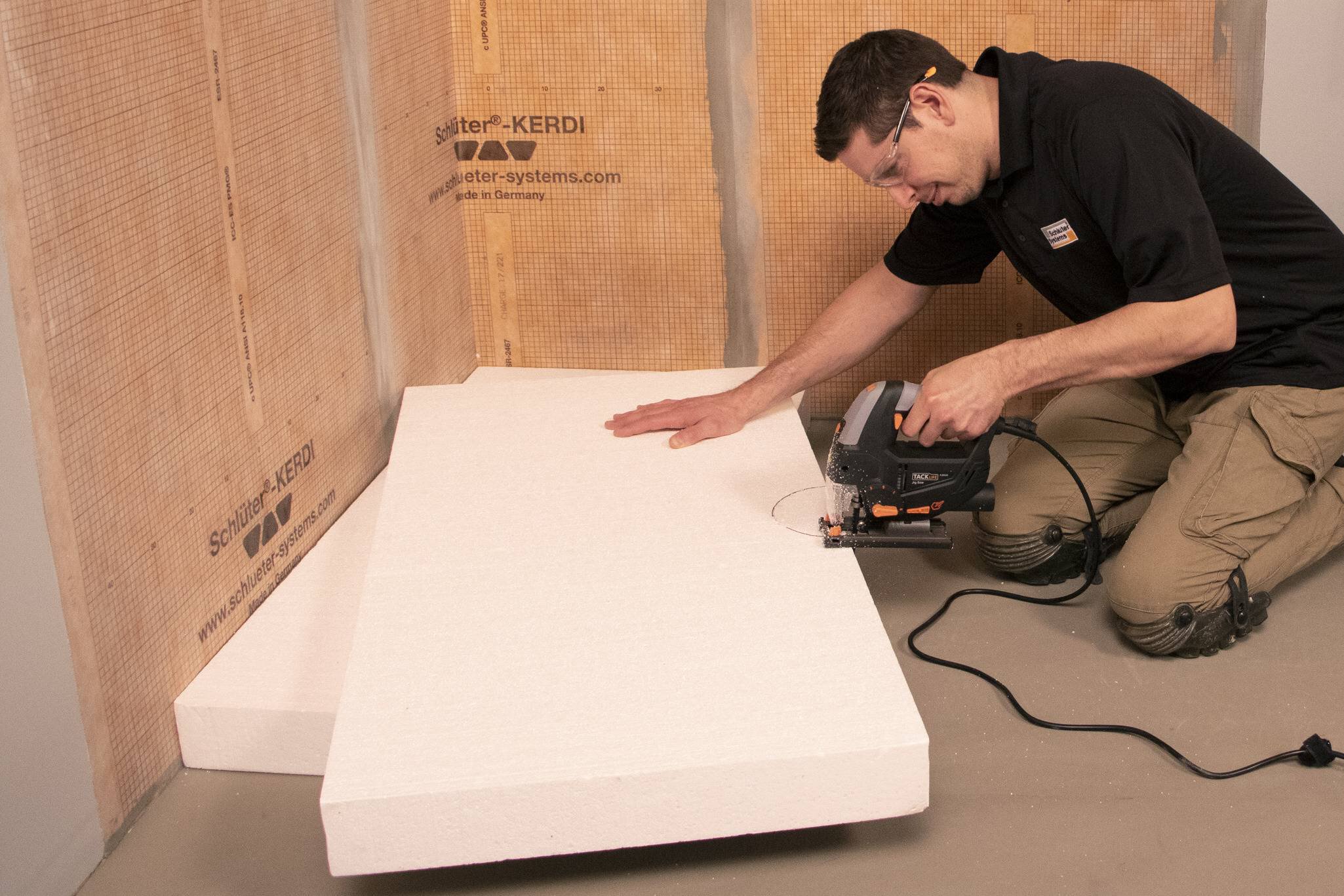 Un homme utilise une scie sauteuse pour découper une plaque de compensation.