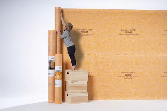 Een jongetje bekijkt verschillende Schl&uuml;ter-KERDI-afdichtingsproducten.