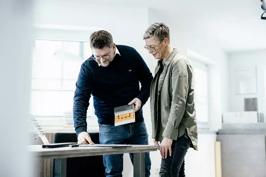 Handelaar van Schl&uuml;ter-systeemproducten zit achter een computer.