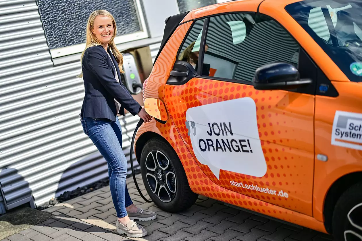 Une employ&eacute;e recharge la Smart de l’apprenti de Schl&uuml;ter-System &agrave; une borne de recharge.