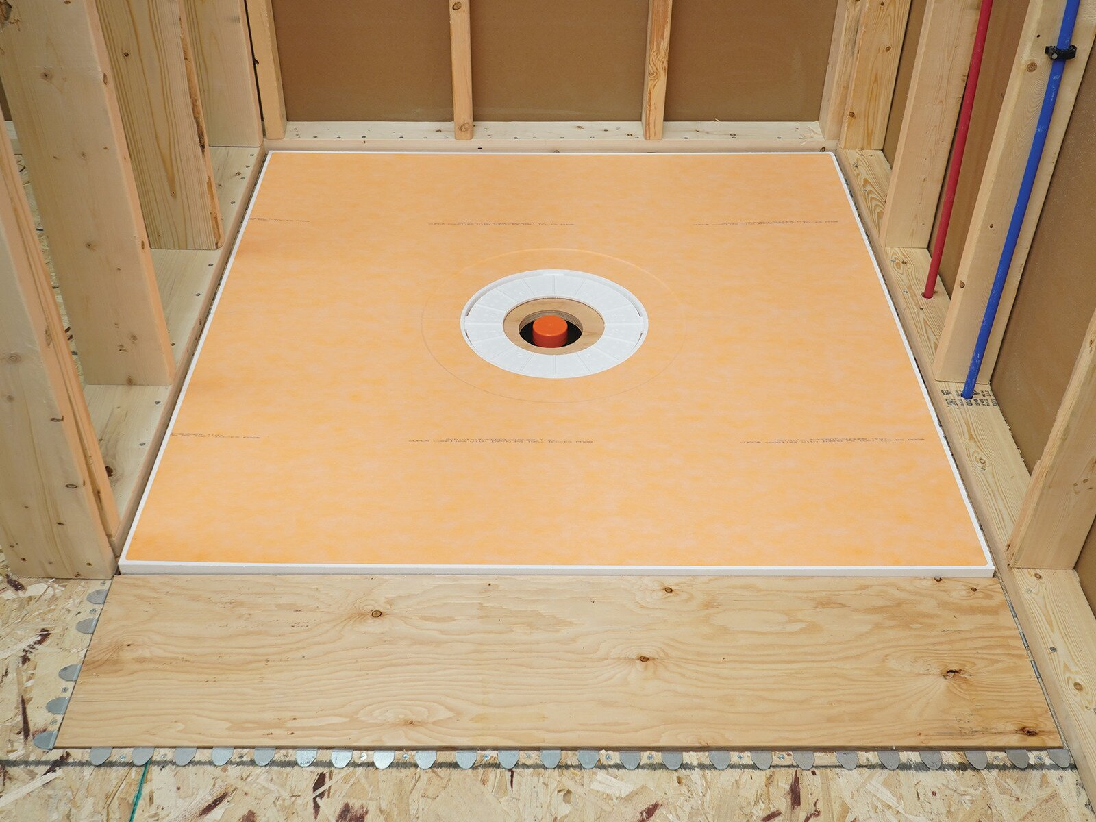 Schluter Systems shower tray set flush in a curbless recess, KERDI-SHOWER-FRS brackets visible along the front edge